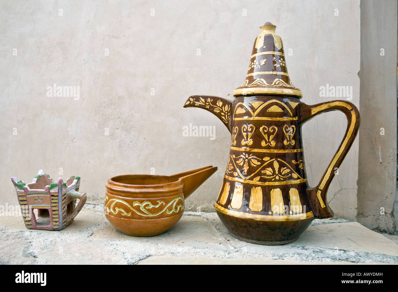 Exemples de types et styles de poterie omanais : cafetière, lampe à huile, l'encens brûleur, sur un rebord de pierre à l'extérieur de la forteresse de Nakhl Banque D'Images
