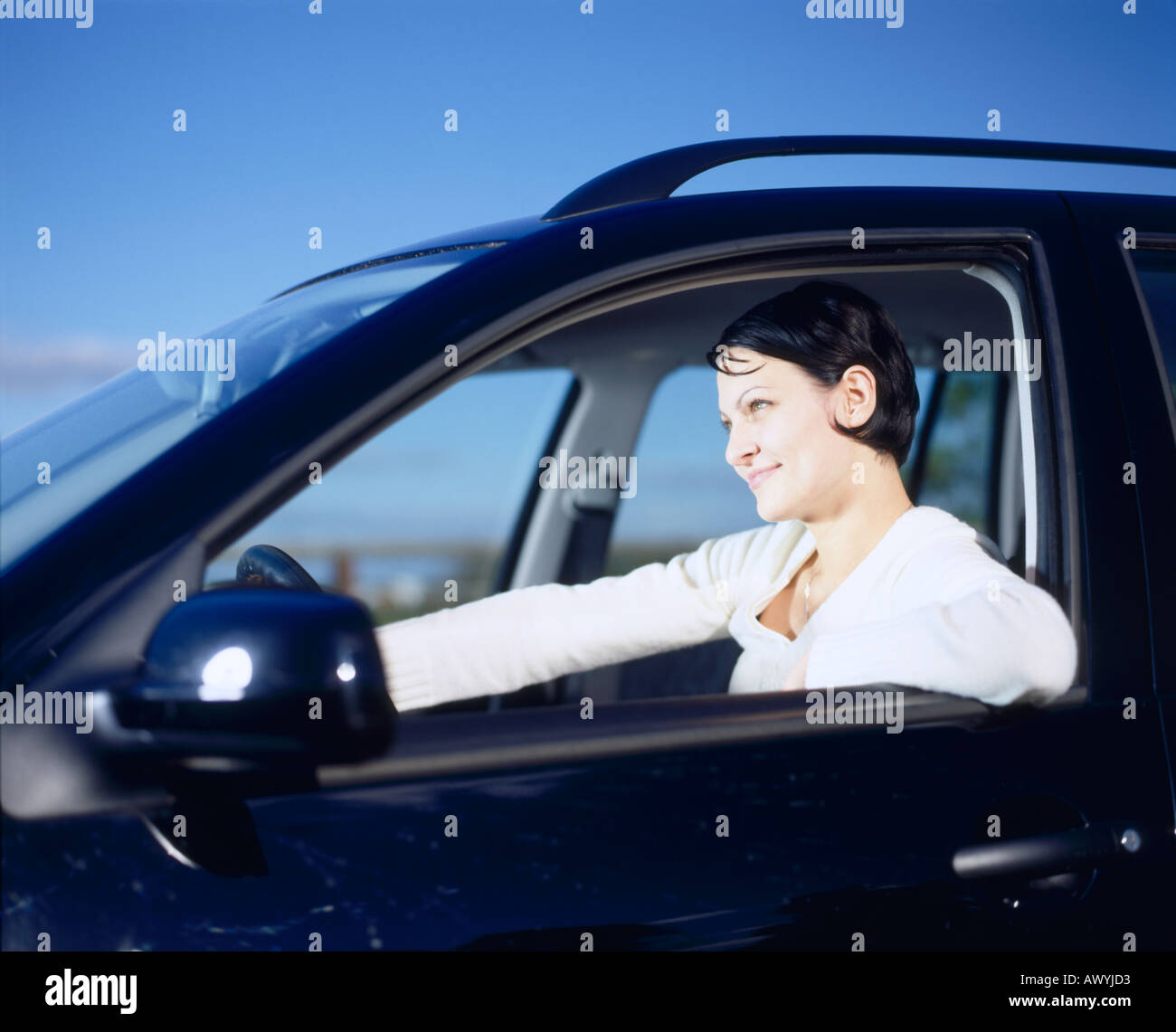 Jeune femme au volant de voiture - vue latérale Banque D'Images