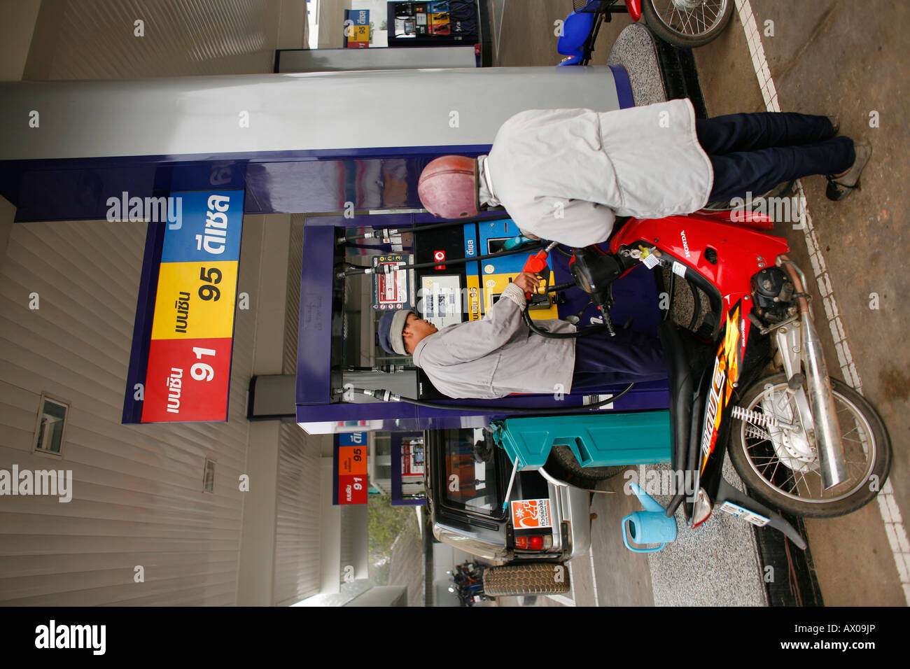 Un cyclomotoriste remplit son réservoir d'essence dans une grande station service à Bangkok Banque D'Images