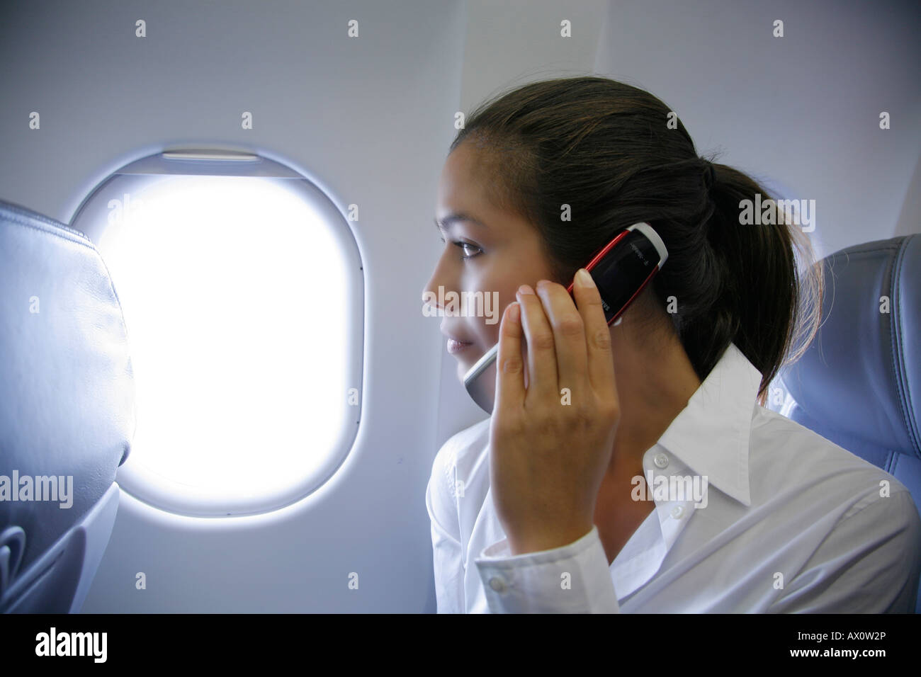 Jeune femme parlant sur un téléphone mobile sur un avion, monsieur-03-03-2008-2 Banque D'Images