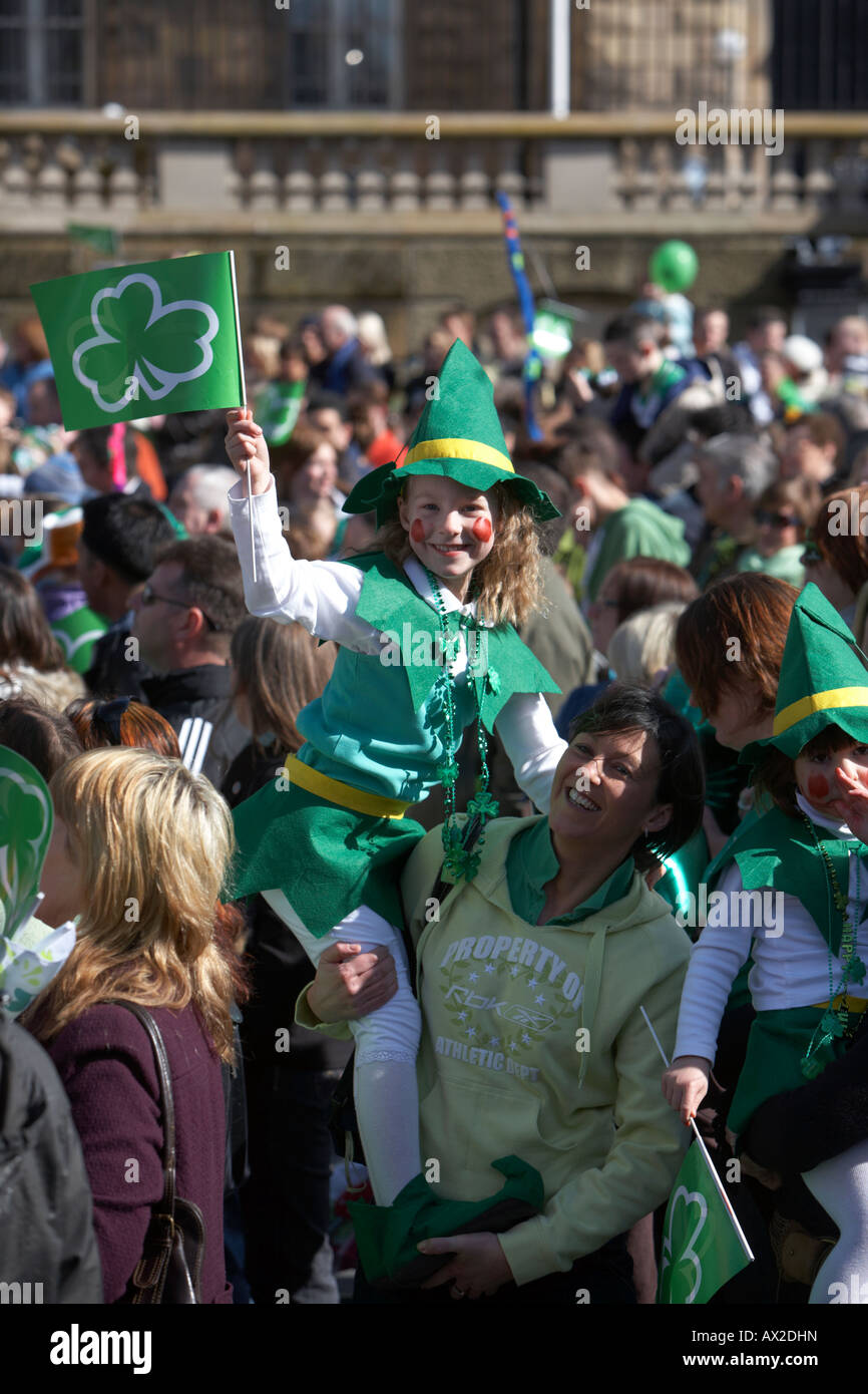 Jeune fille dans fancy dress costume irlandais waving flag tenue par mère dans la foule au concert et carnaval à custom house Banque D'Images