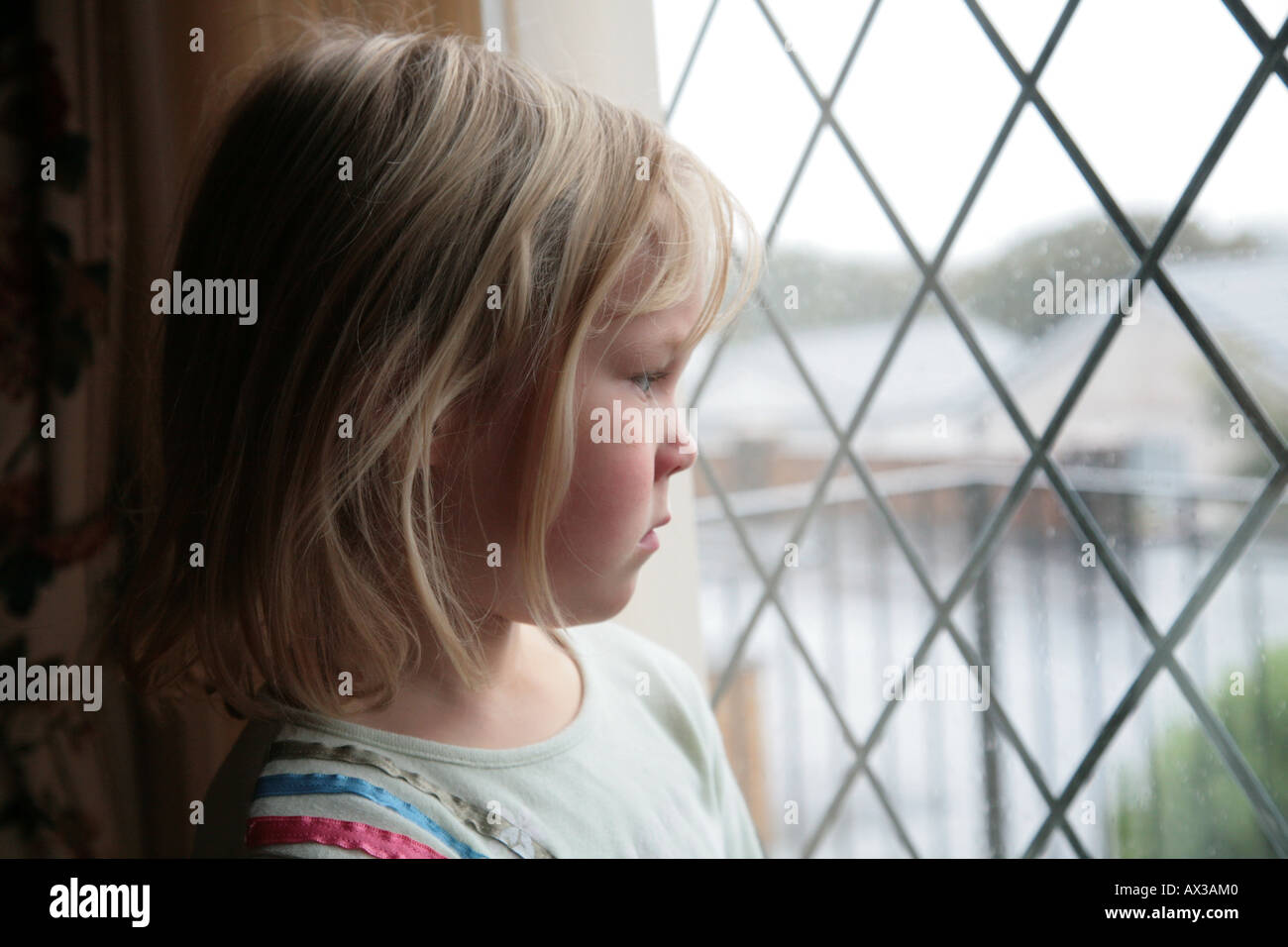 Triste jeune fille à la fenêtre par jour sur sol mouillé Banque D'Images