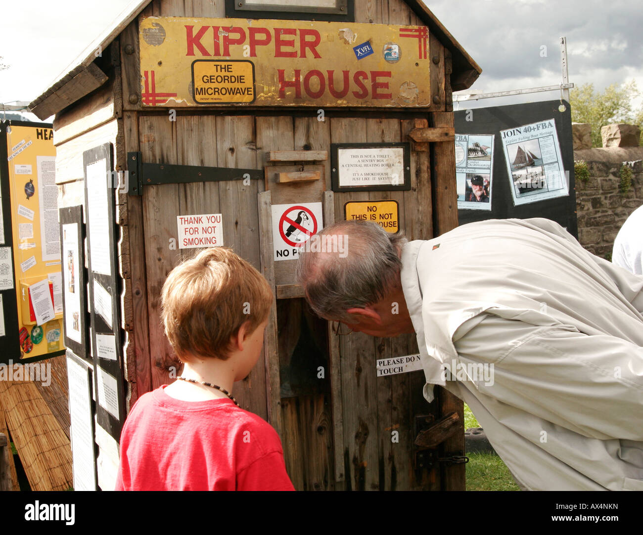 L'homme et de garçon à la recherche de la fenêtre d'une maison en bois fumée kipper Banque D'Images