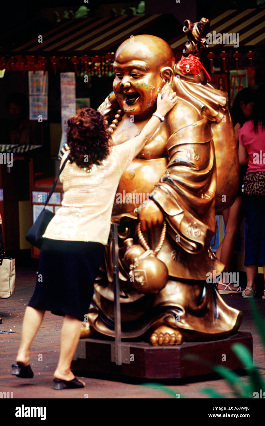 Une femme se frotte le visage d'une statue de Bouddha à Singapour. La loi est censée porter chance. Banque D'Images