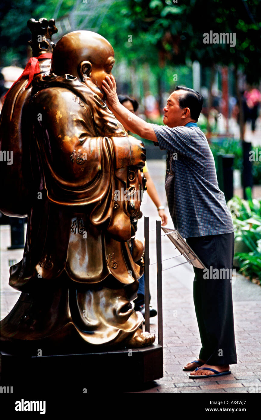 Un homme se frotte le visage d'une statue de Bouddha à Singapour. Cette loi est censée porter chance. Banque D'Images
