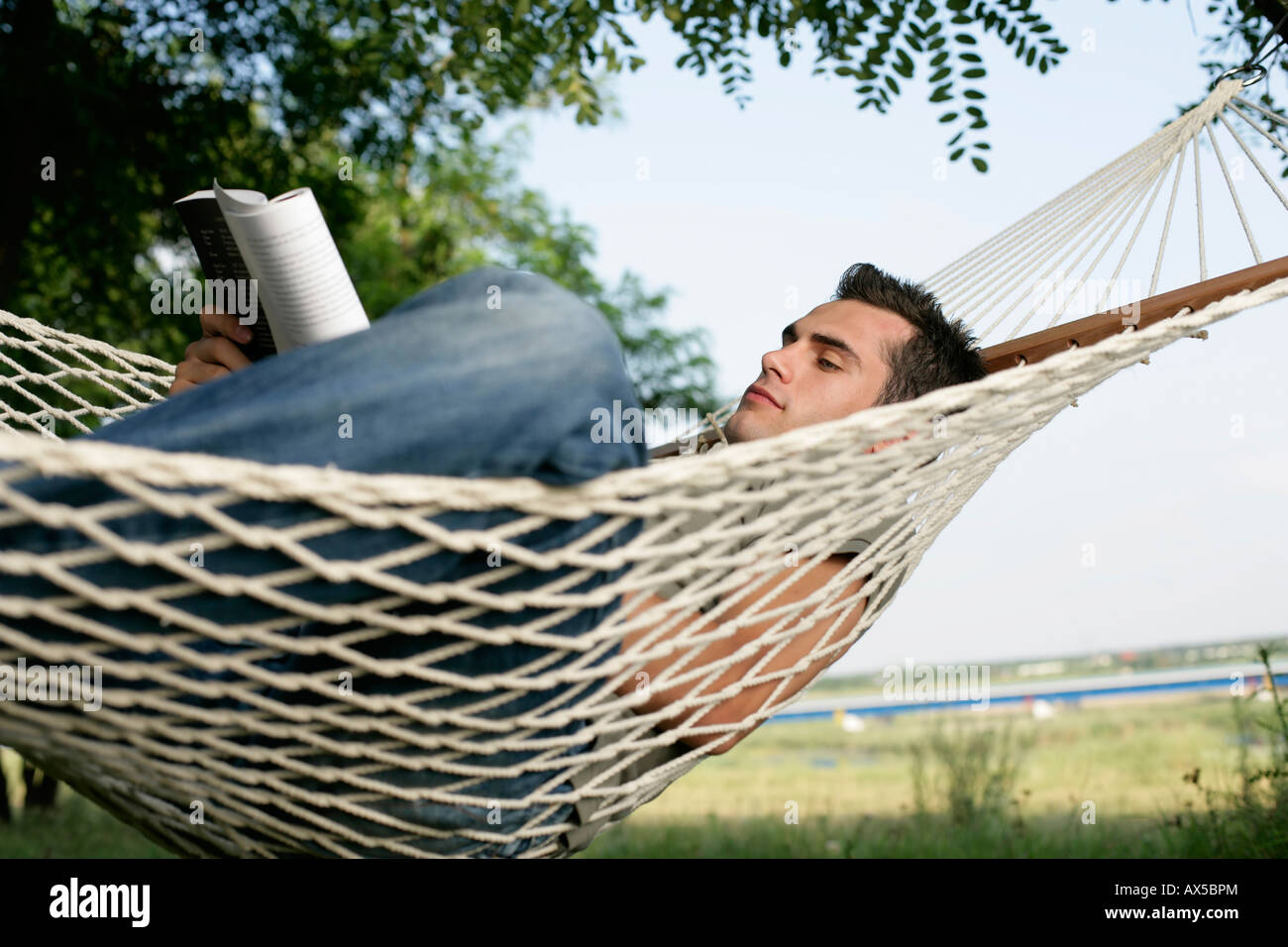 L'homme couché dans un hamac et de la lecture Photo Stock - Alamy