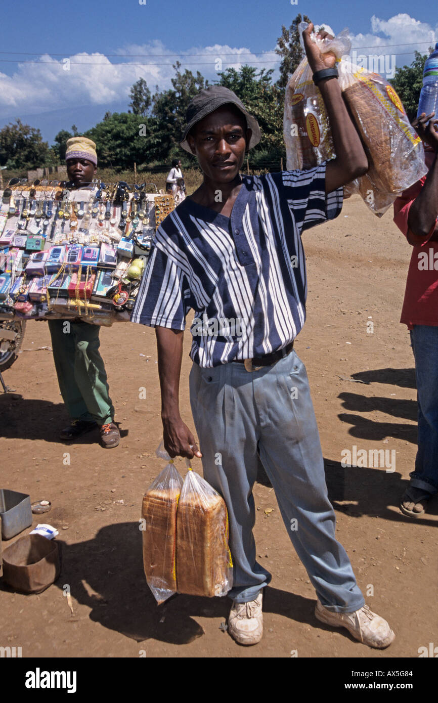 Jeune homme travaillant comme camelots vend du pain à une station de bus, Moshi, Tanzanie Banque D'Images