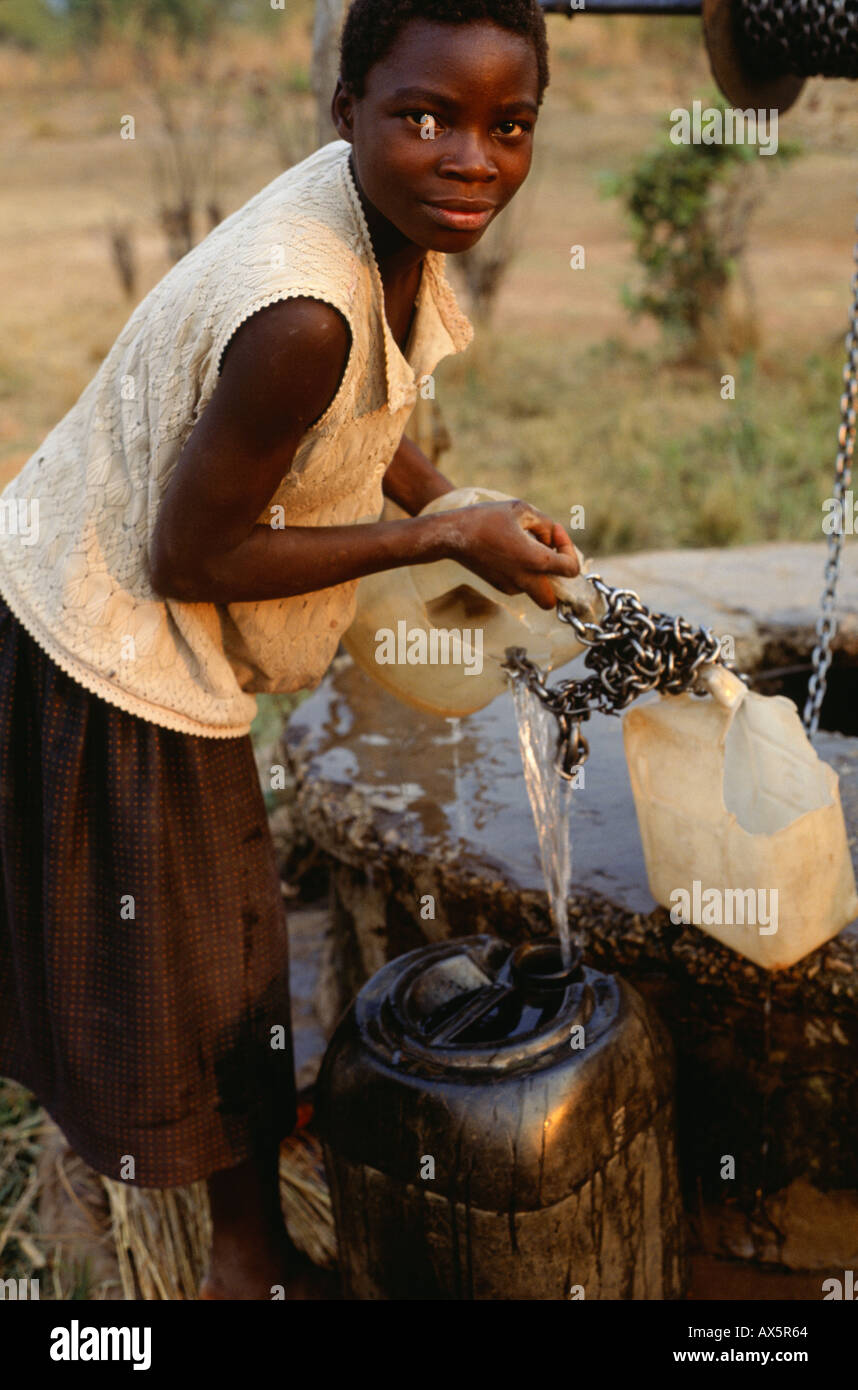 Kapatu, Zambie. Remplissage de l'eau sa femme containter au puits du village. Banque D'Images