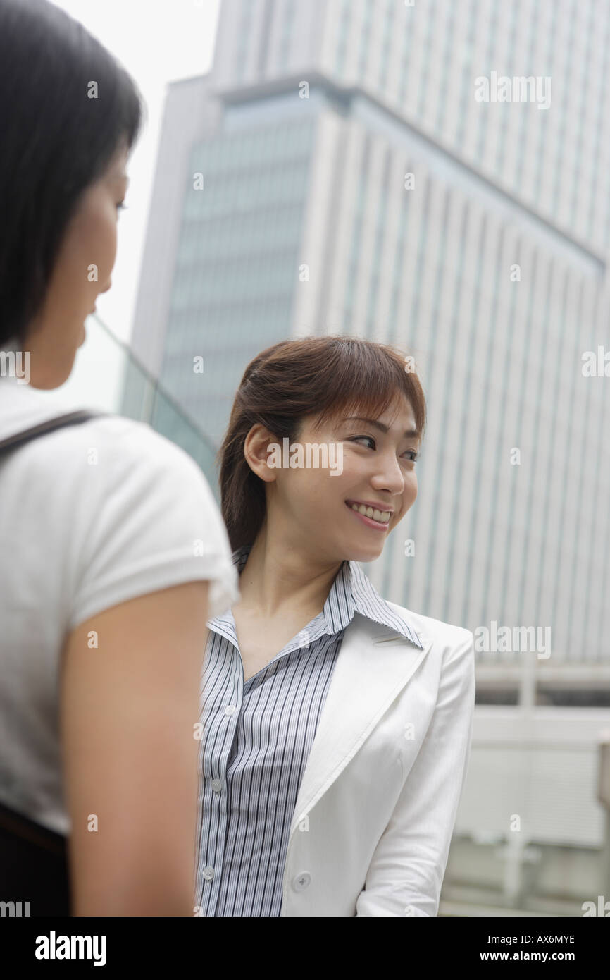 Une femme heureuse en regardant quelque chose avec un bâtiment commercial à l'arrière-plan Banque D'Images