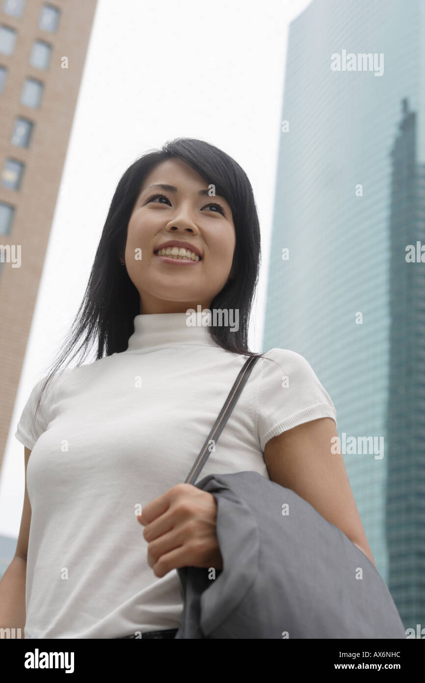 Une femme souriante avec des gratte-ciel à l'arrière-plan Banque D'Images