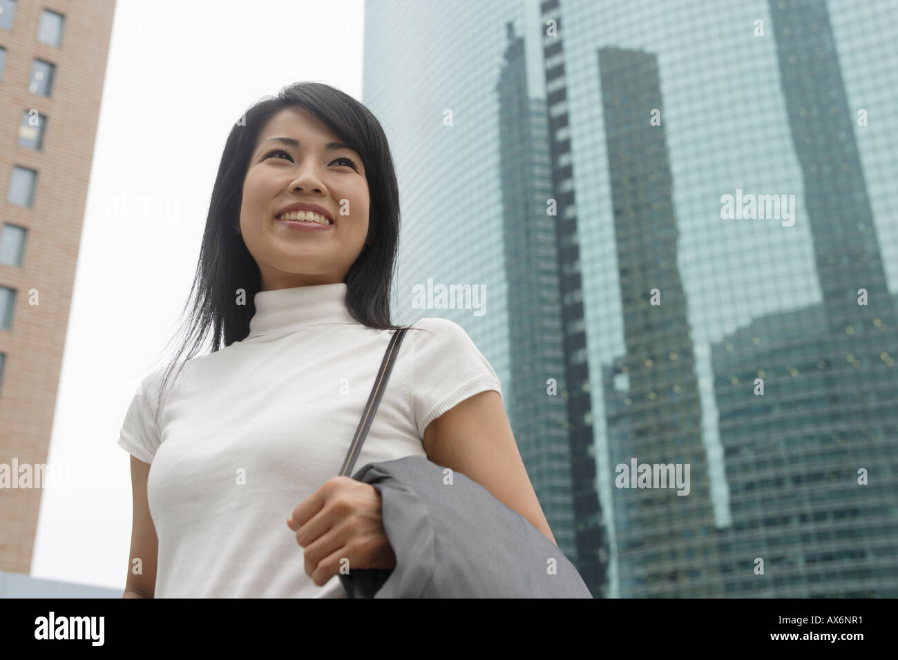 Une femme souriante avec des gratte-ciel à l'arrière-plan Banque D'Images