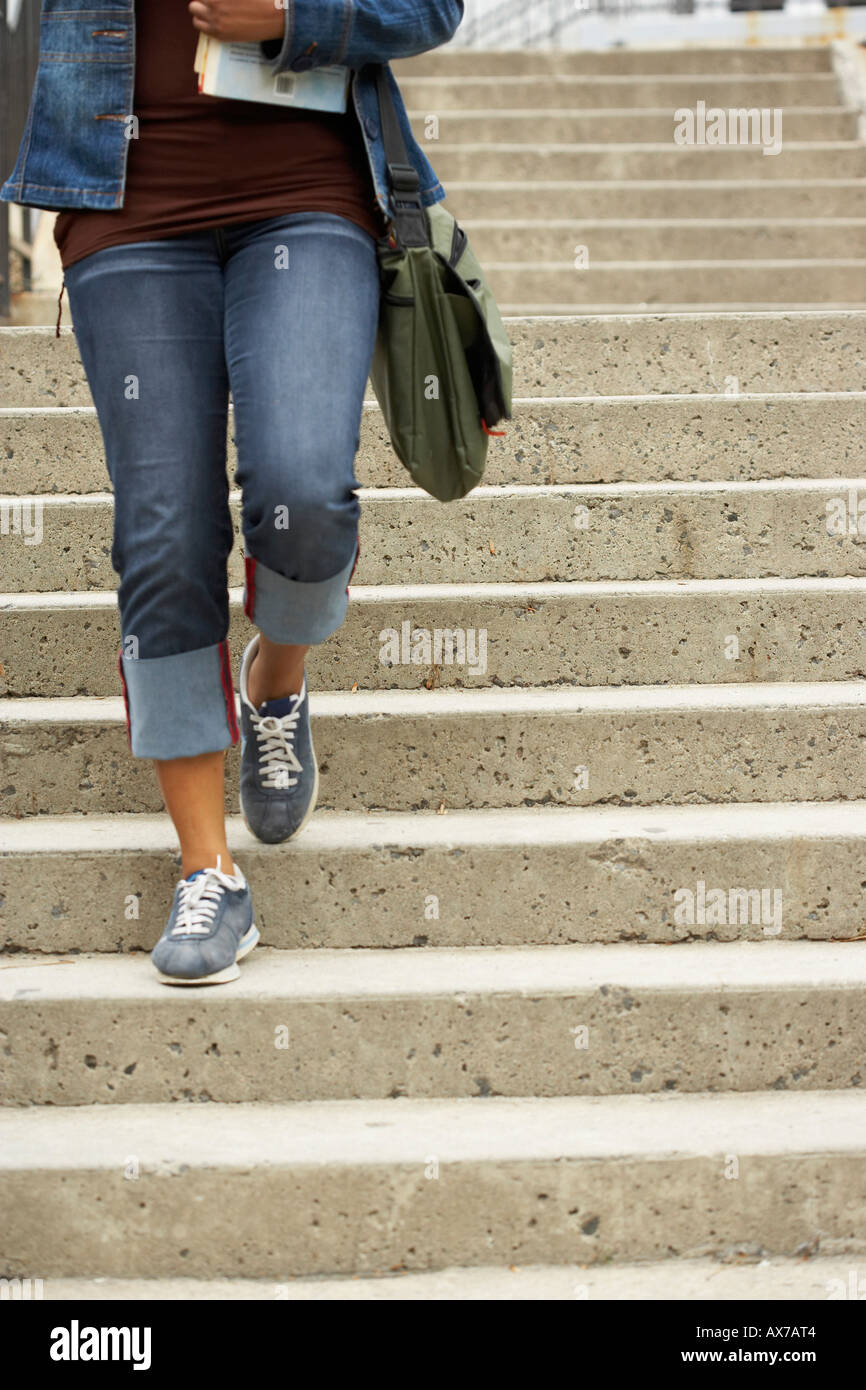Close-up of a college student en descendant un escalier et portant des livres Banque D'Images