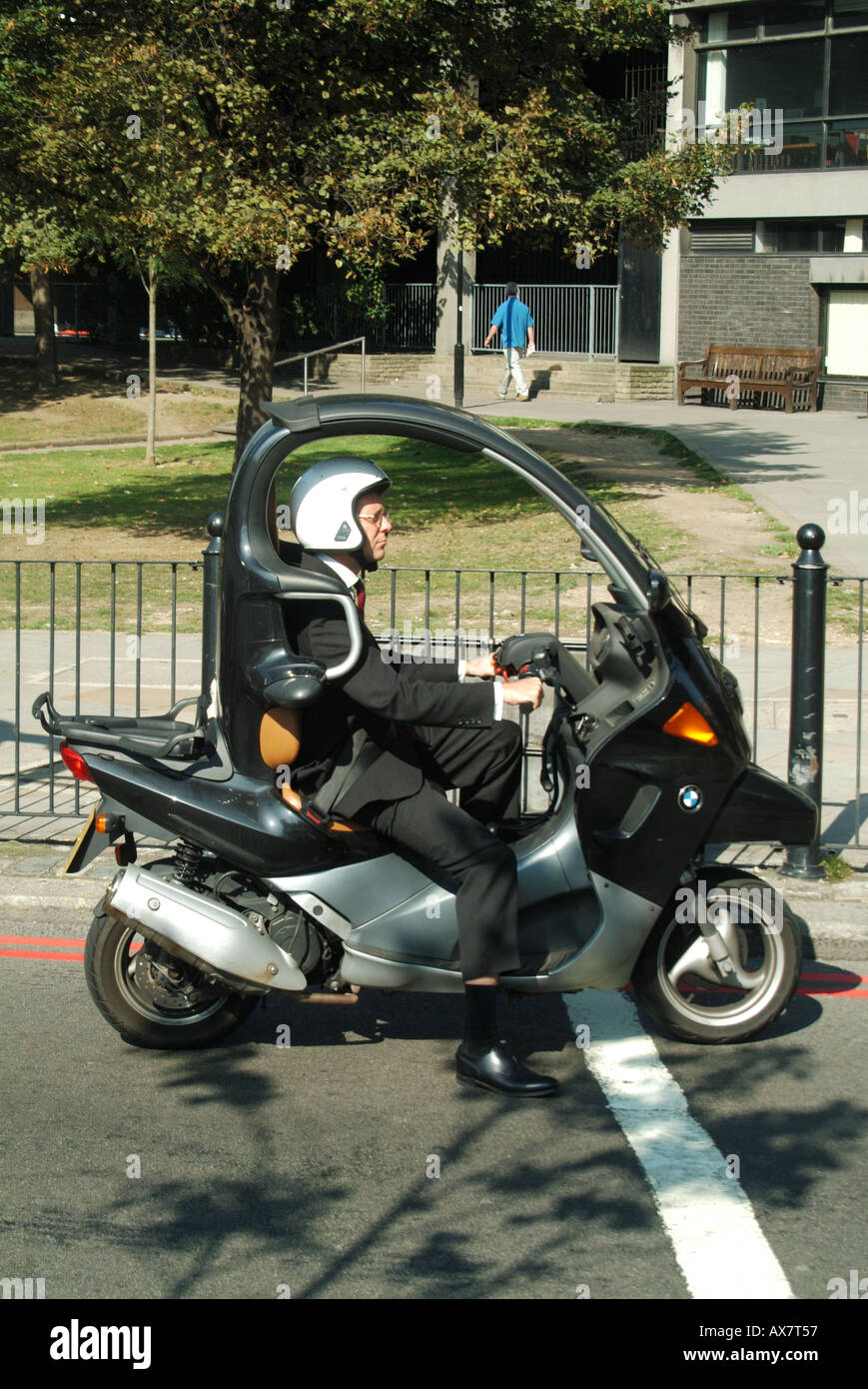 L'homme en costume de bureau de Londres la conduite d'un scooter l'attente aux feux de circulation Banque D'Images
