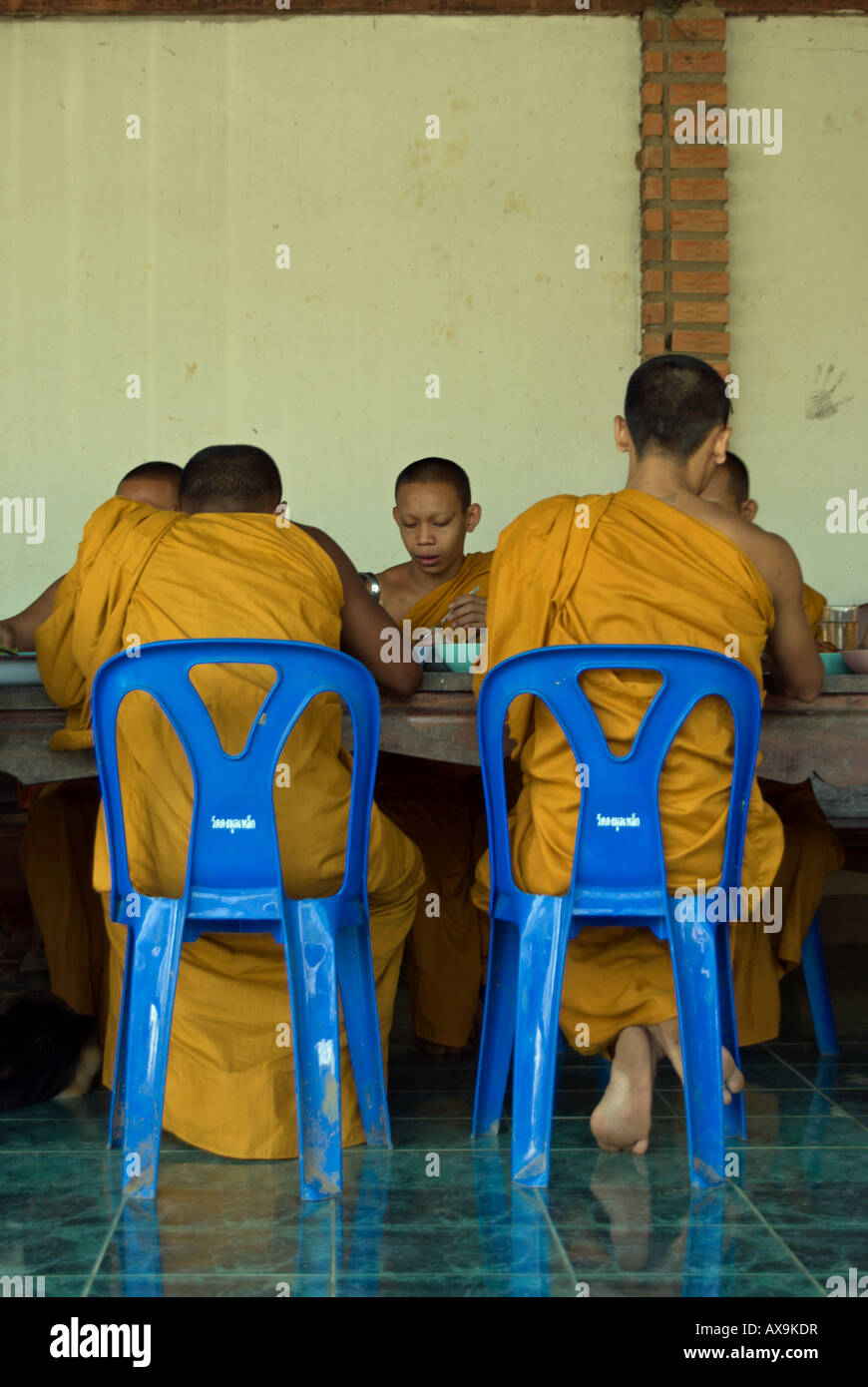 Assis sur des chaises en plastique bleu à une table , thai moines bouddhistes en robe jaune manger un délicieux repas dans un temple près de Phetchabun, Thaïlande Banque D'Images