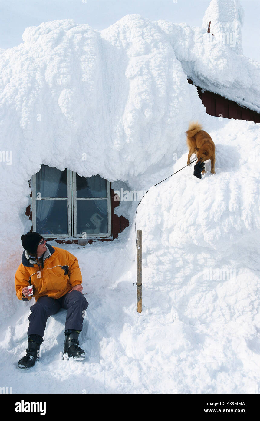 L'homme et le chien en face d'un refuge de montagne dans la neige, Areskutan, sont, en Suède Banque D'Images