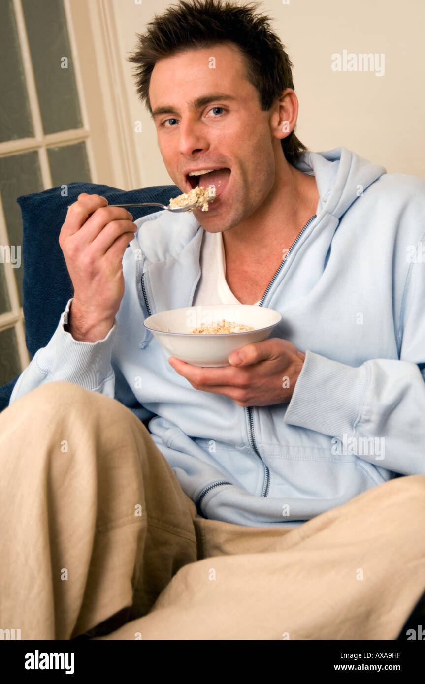 Homme assis sur un canapé et manger un bol de céréales Banque D'Images
