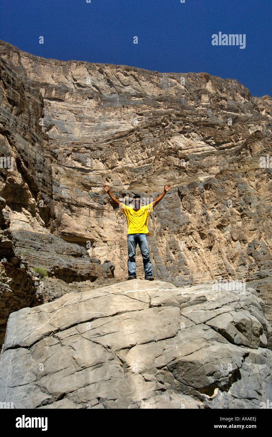 Un homme dans une chemise jaune du Wadi Nakhr, près de l'Oued Ghool à Jebel Akhdar dans l'Ouest de montagnes Hajar du sultanat d'Oman. Banque D'Images