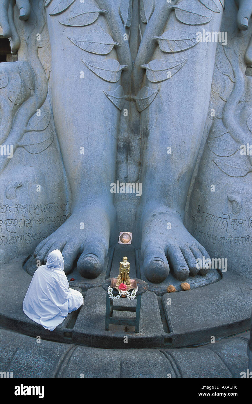 Une personne se recroquevillant devant les pieds de la statue géante Sri Gometeswara, Sravanabelagola, Karnataka, Inde Banque D'Images