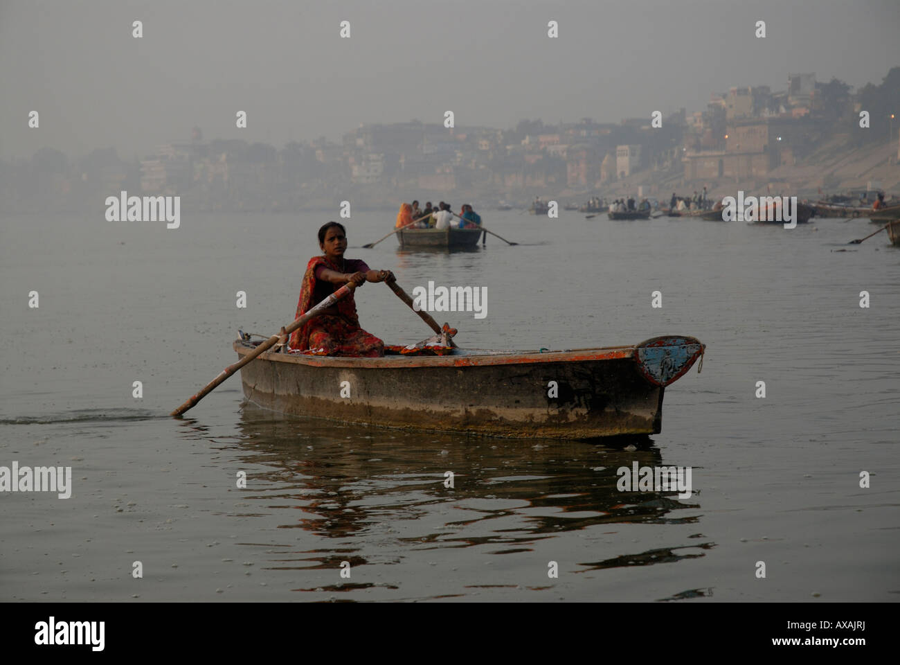 L'aube, un batelier lignes son bateau pour travailler sur le Gange, le fleuve sacré Varanasi Inde Banque D'Images