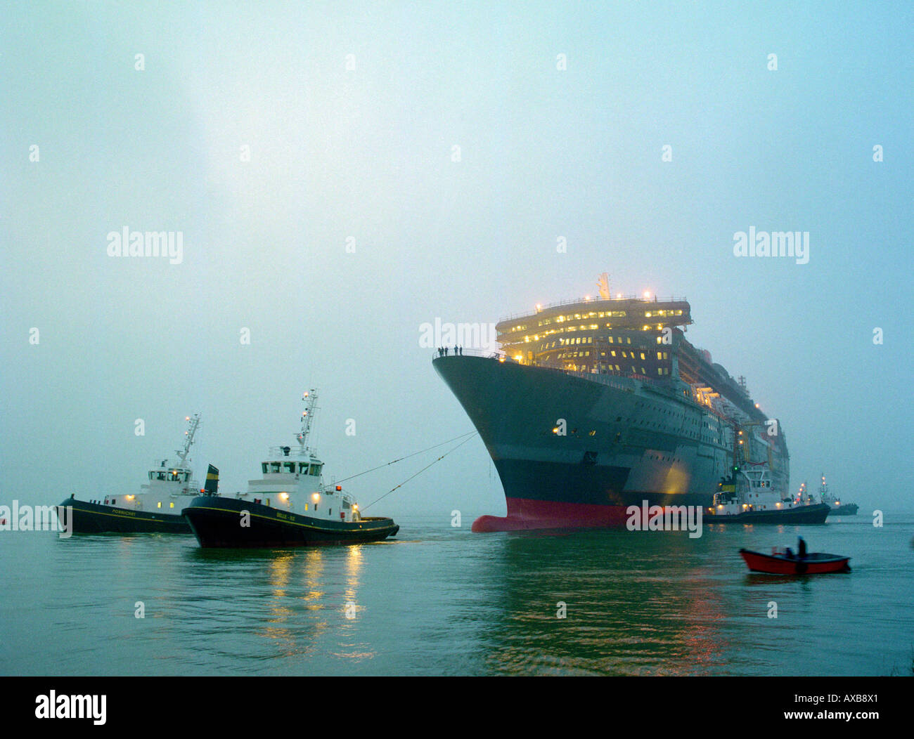 Les remorqueurs tirant sur le navire de croisière Queen Mary 2 à l'aube, Saint-Nazaire, France Banque D'Images