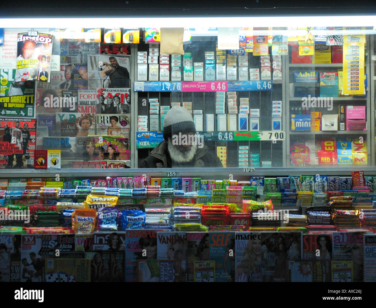 Un homme âgé dans kiosque entouré de produits colorés, USA, Manhattan, New York Banque D'Images