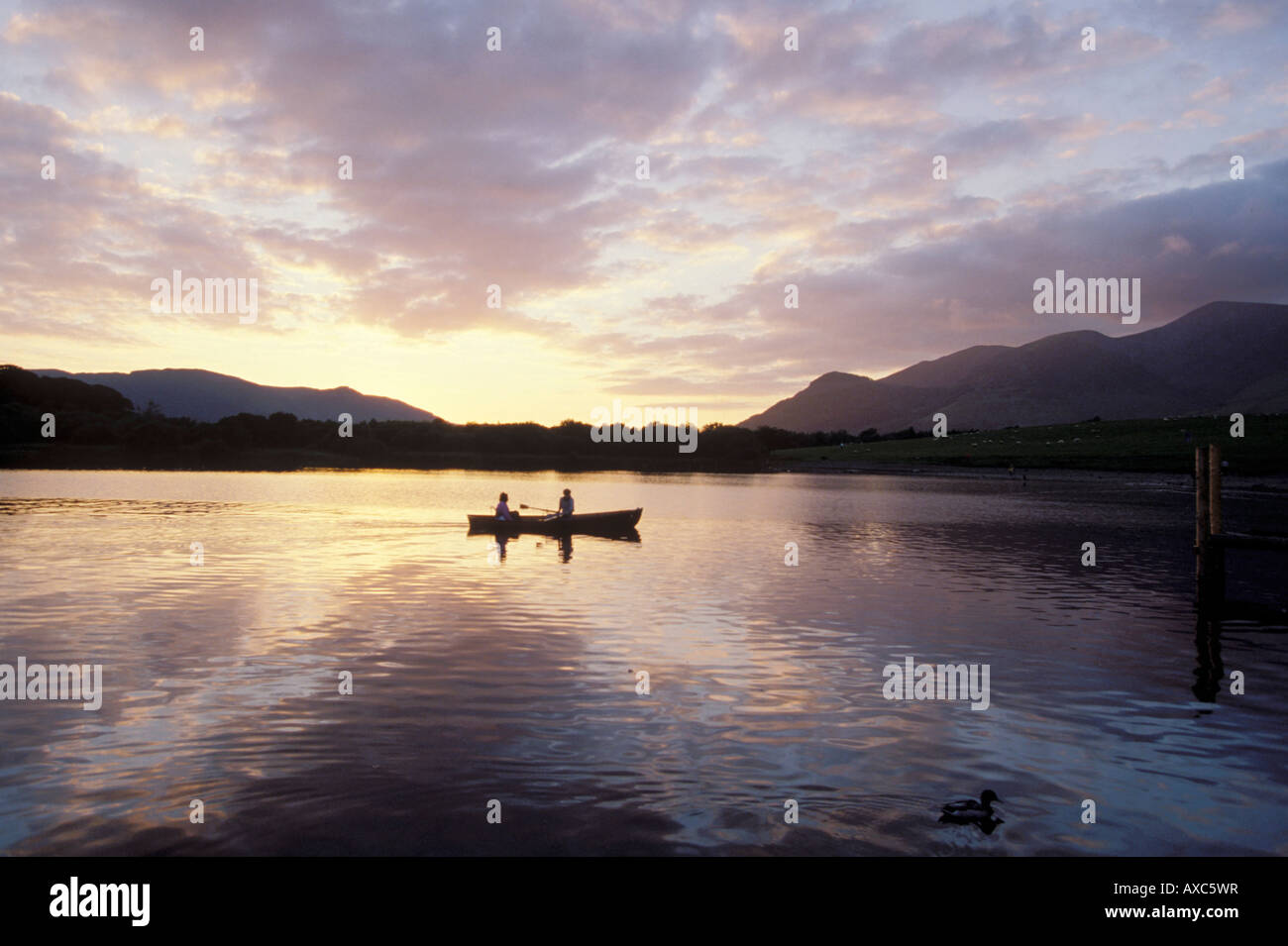 Deux personnes pédalo sur l'eau calme au crépuscule, Lake District, UK Banque D'Images
