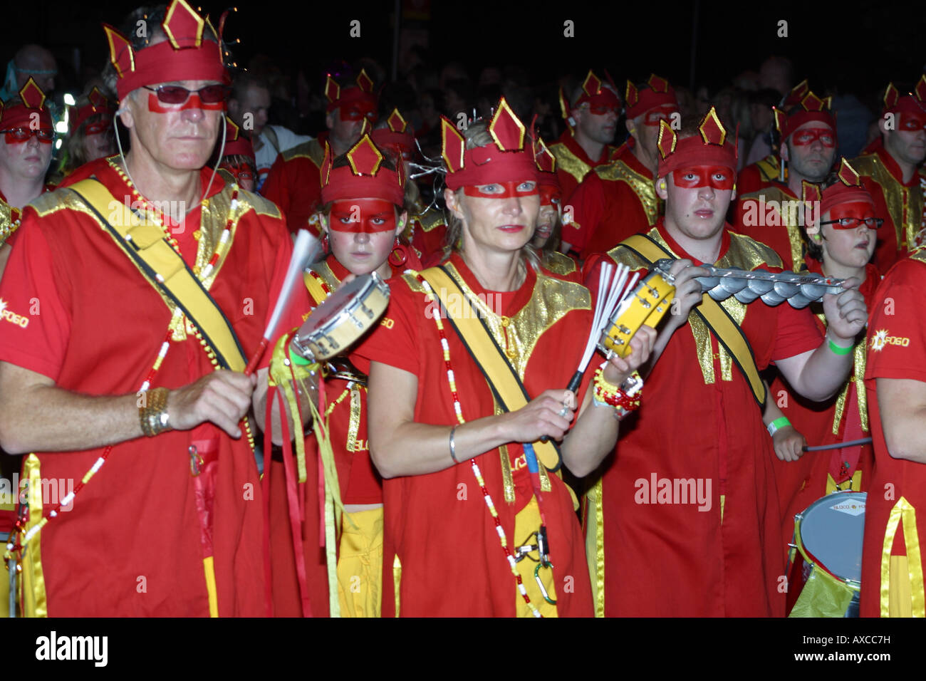 Robe rouge danseuse brésilienne masque marche musiciens Banque D'Images