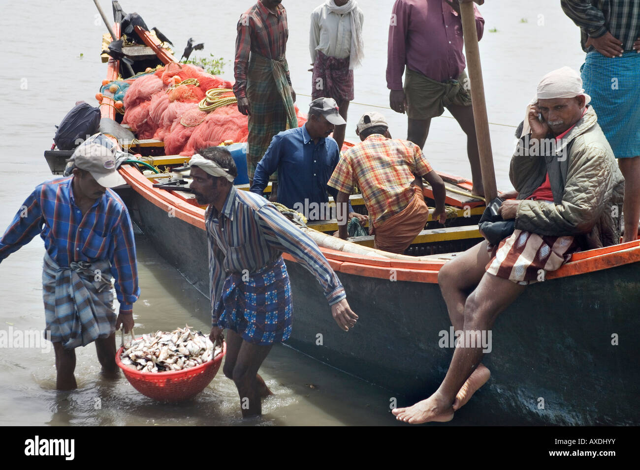 Les pêcheurs en pirogue locale Keralite vallom désactiver chargement captures après expédition de pêche fort Kochi Beach Kerala Inde du Sud Banque D'Images