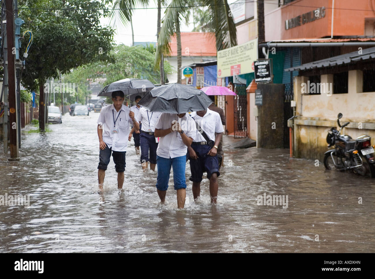 Les jeunes écoliers indiens à gué à l'école par le biais de routes inondées après effet pluie Ernakulam Kerala Inde du Sud Banque D'Images