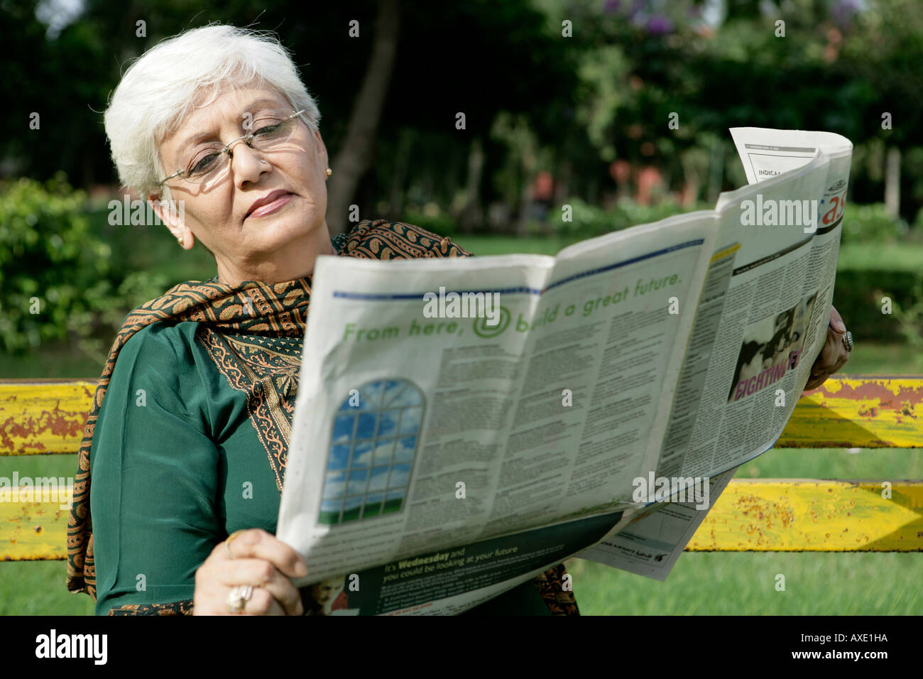 Senior woman reading newspaper in a park Banque D'Images