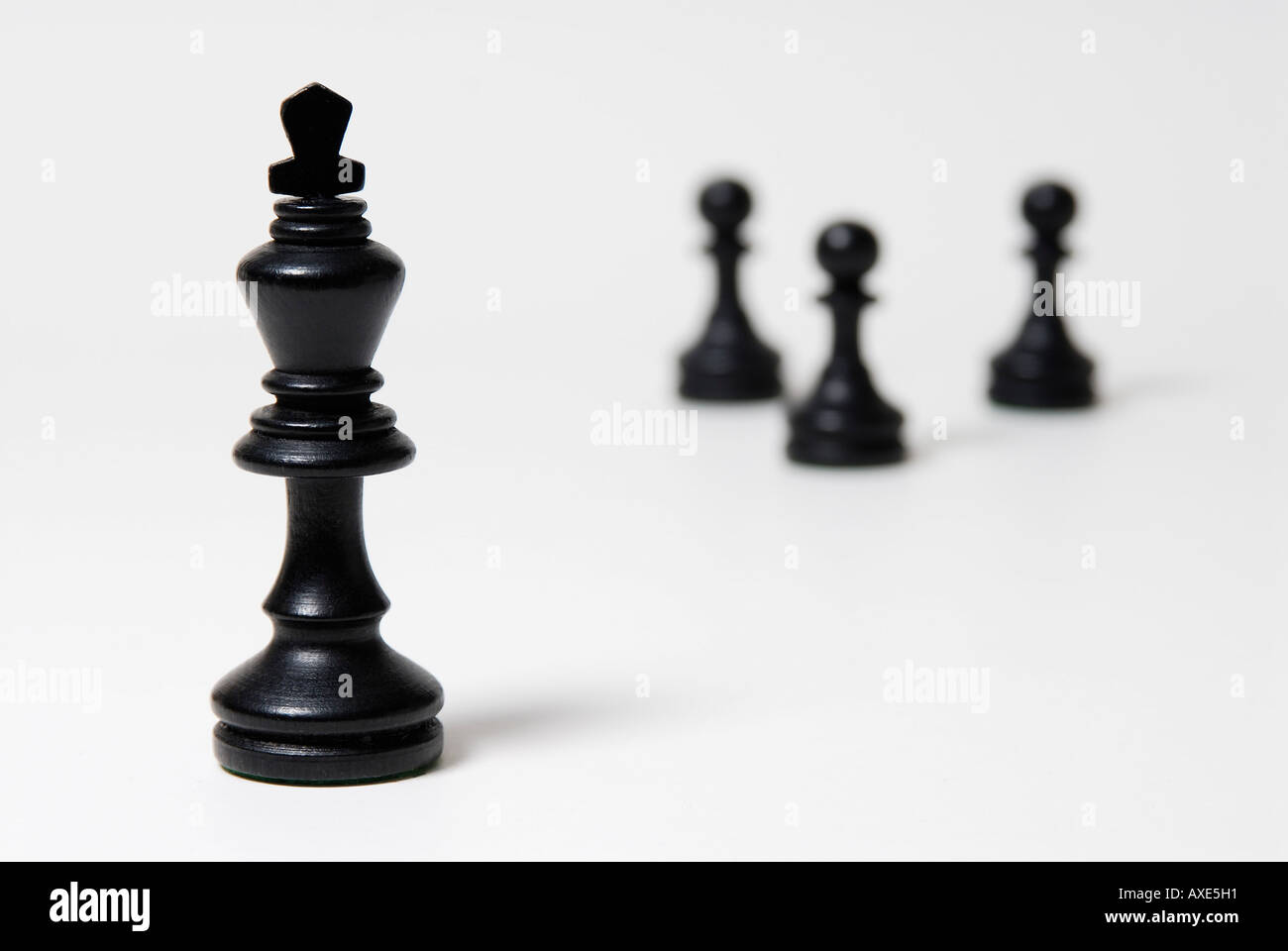 Les échecs, l'un roi noir se trouve en face d'un petit groupe de pions noirs, symbole de domination, de leadership Banque D'Images