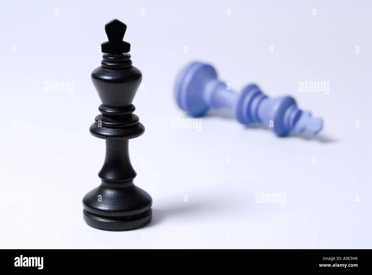 Les échecs, l'un roi noir se trouve en face d'un bleu roi tombé, symbole de victoire, défaite Banque D'Images