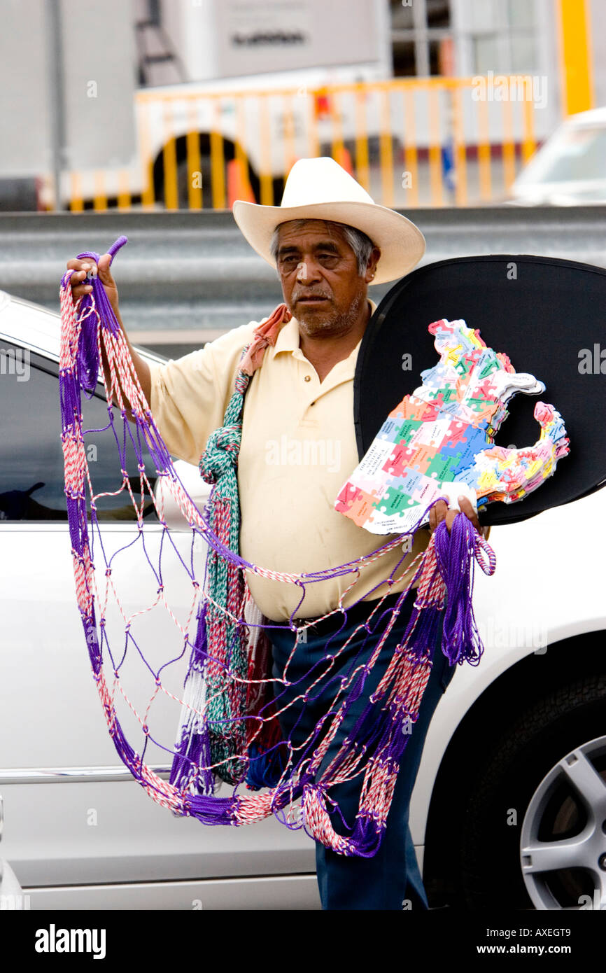 Le vendeur mexicain vend des bibelots colorés aux conducteurs et aux passagers qui attendent dans des véhicules au poste frontalier Mexique-États-Unis. Banque D'Images