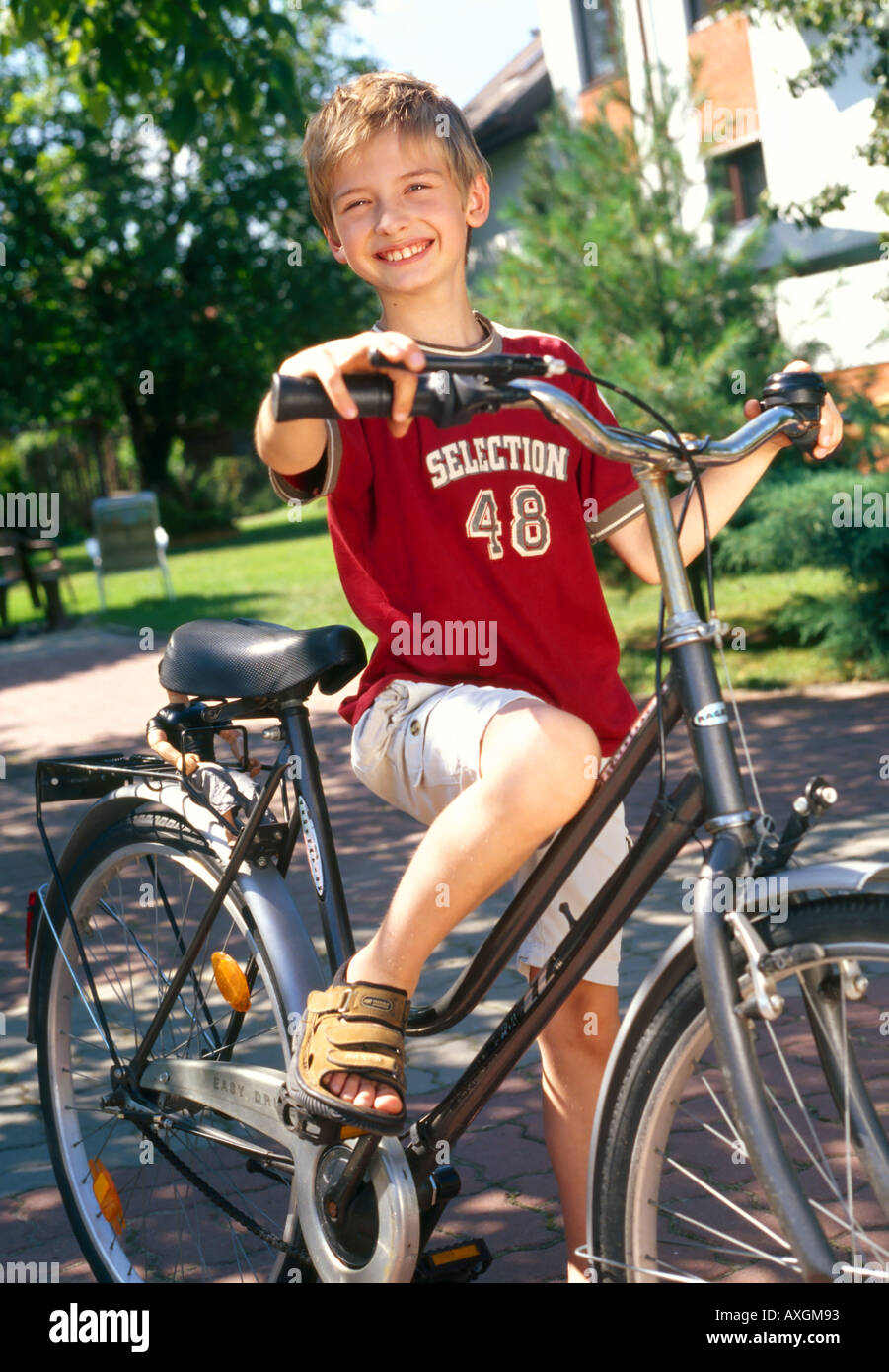 Jour d'été en plein air jardin enfant garçon blond 510 sit stand plomb tenir vélo loisirs détente vacances sourire vertica Banque D'Images