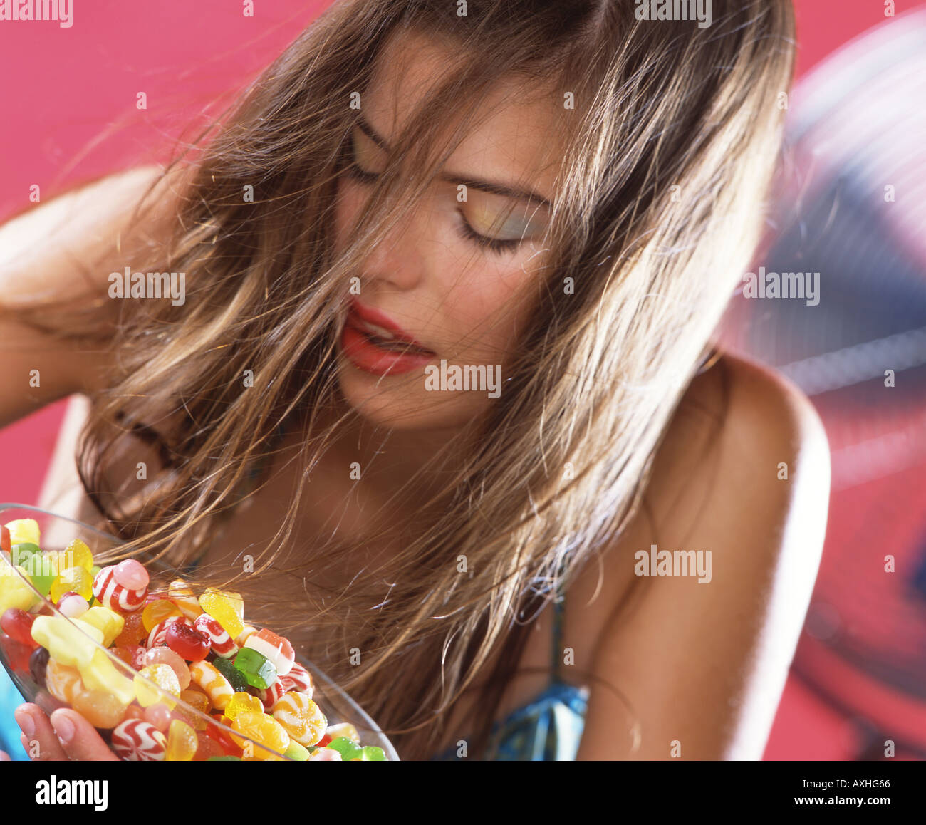 Young woman eating jelly beans à partir d'un grand bol. Banque D'Images