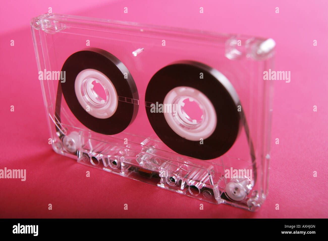 Cassette audio transparent sur fond rose. Banque D'Images
