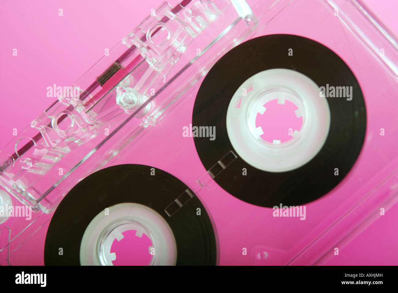 Gros plan d'une cassette audio transparent sur fond rose. Banque D'Images