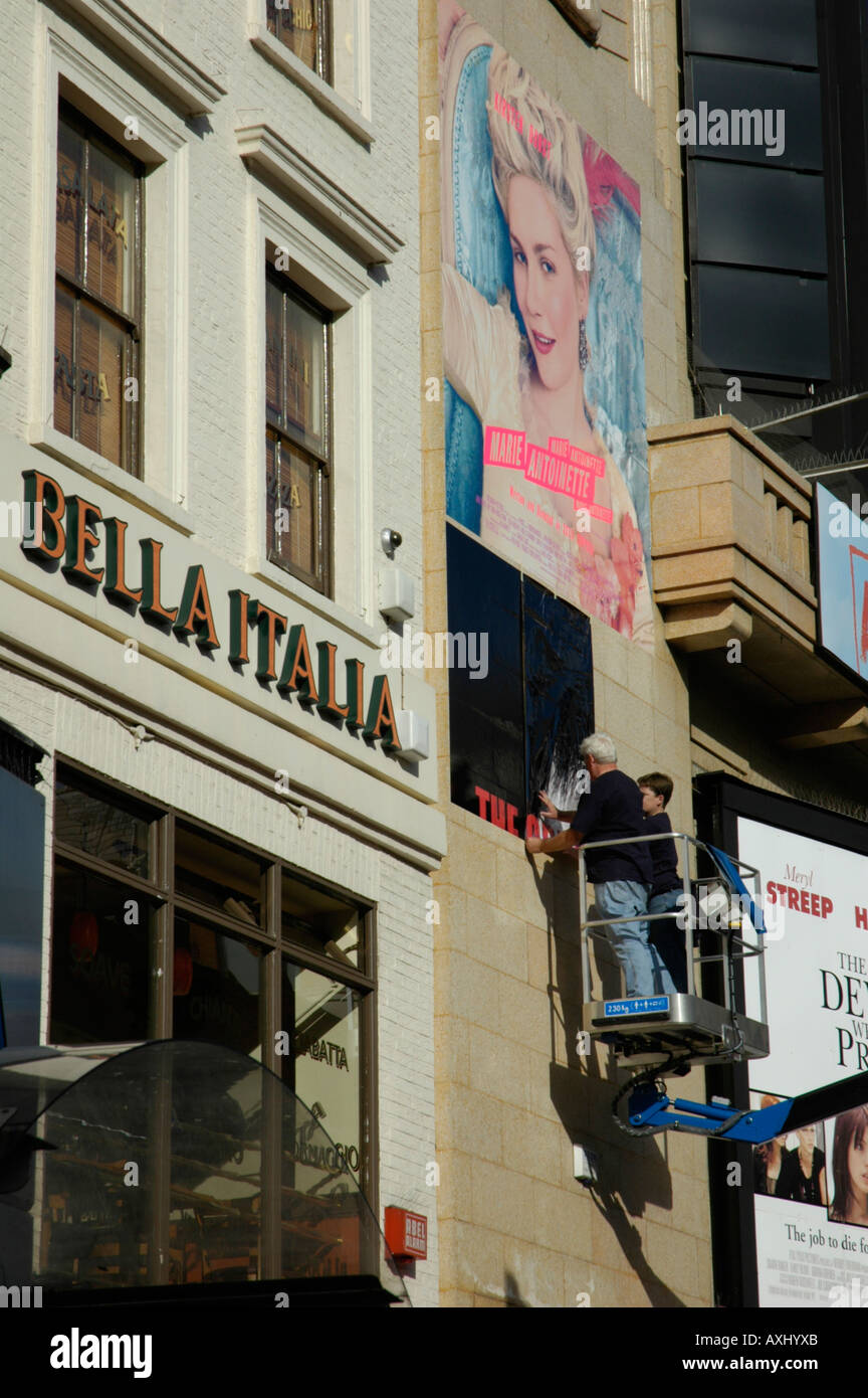 Ouvriers érigeant des affiches de films publicitaires en dehors de salles dans Leicester Square Londres Angleterre Banque D'Images