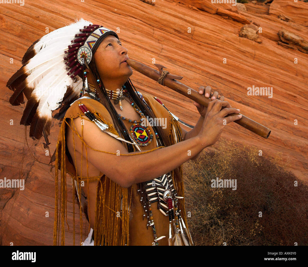 Native American Indian man personne avec équipement culturel plumes coiffe uniforme de la lecture de musique sifflet corne instrument Banque D'Images