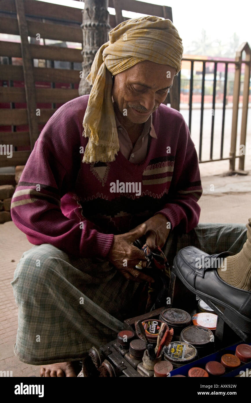 Pieds nus un homme exécute un cireur business près du BBD Bagh domaine de Kolkata. Il polit une place du client. Banque D'Images