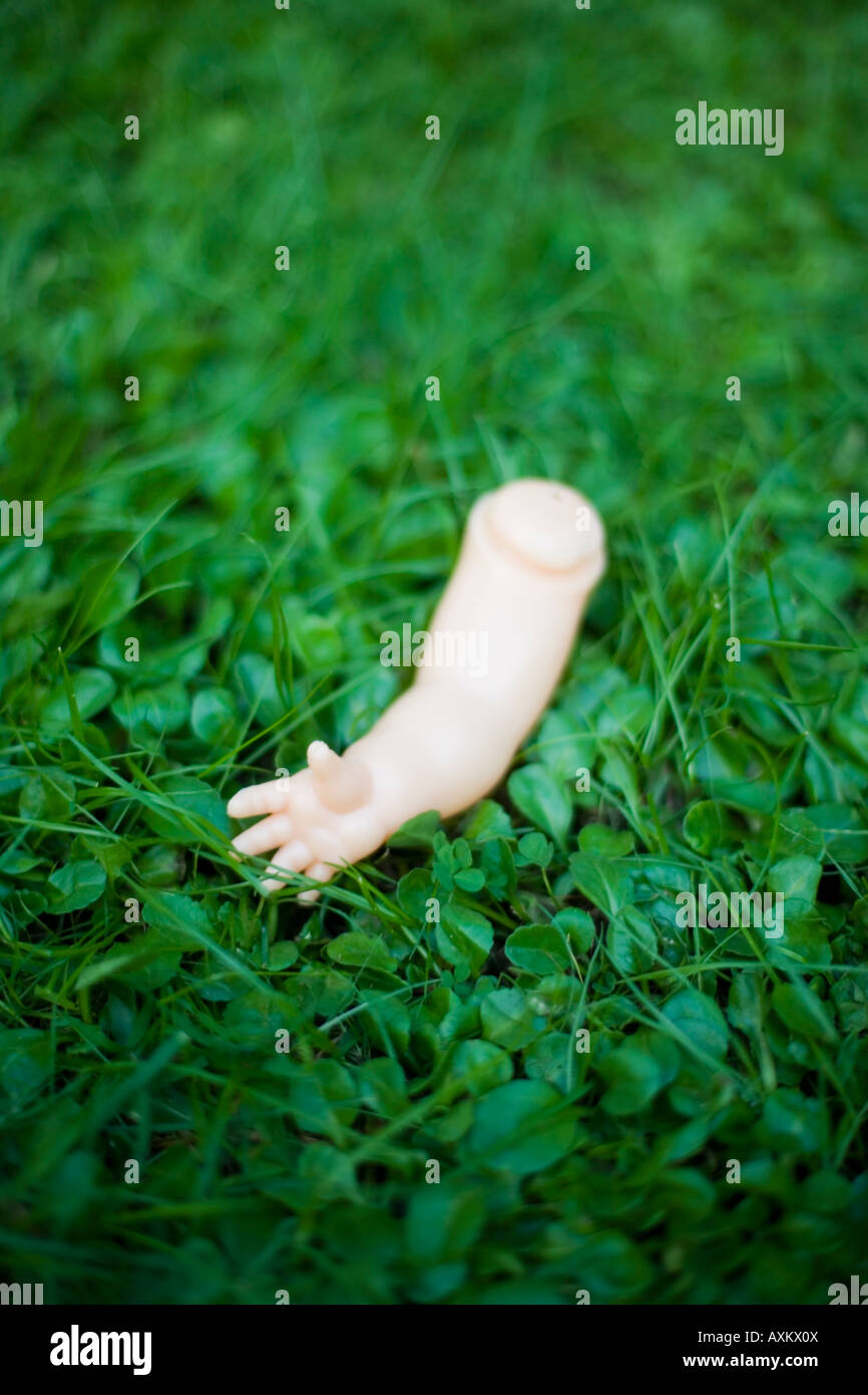 Le bras de poupée en plastique jetés sur la pelouse Banque D'Images