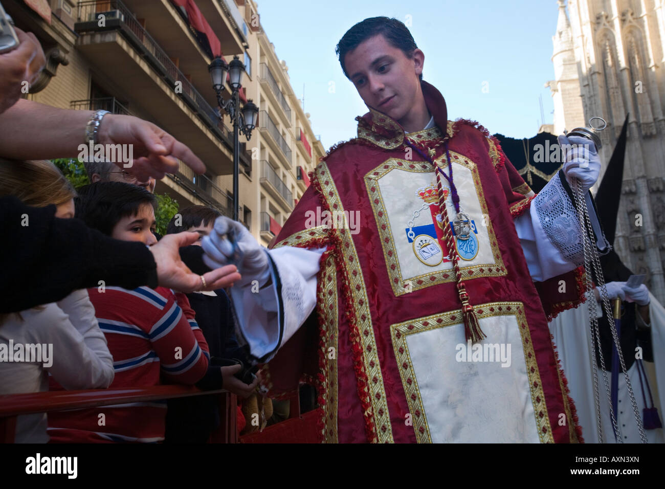 Un acolyte donne les spectateurs des cartes avec des images de ses images de fraternité au cours d'une procession de la Semaine Sainte, Séville, Espagne Banque D'Images