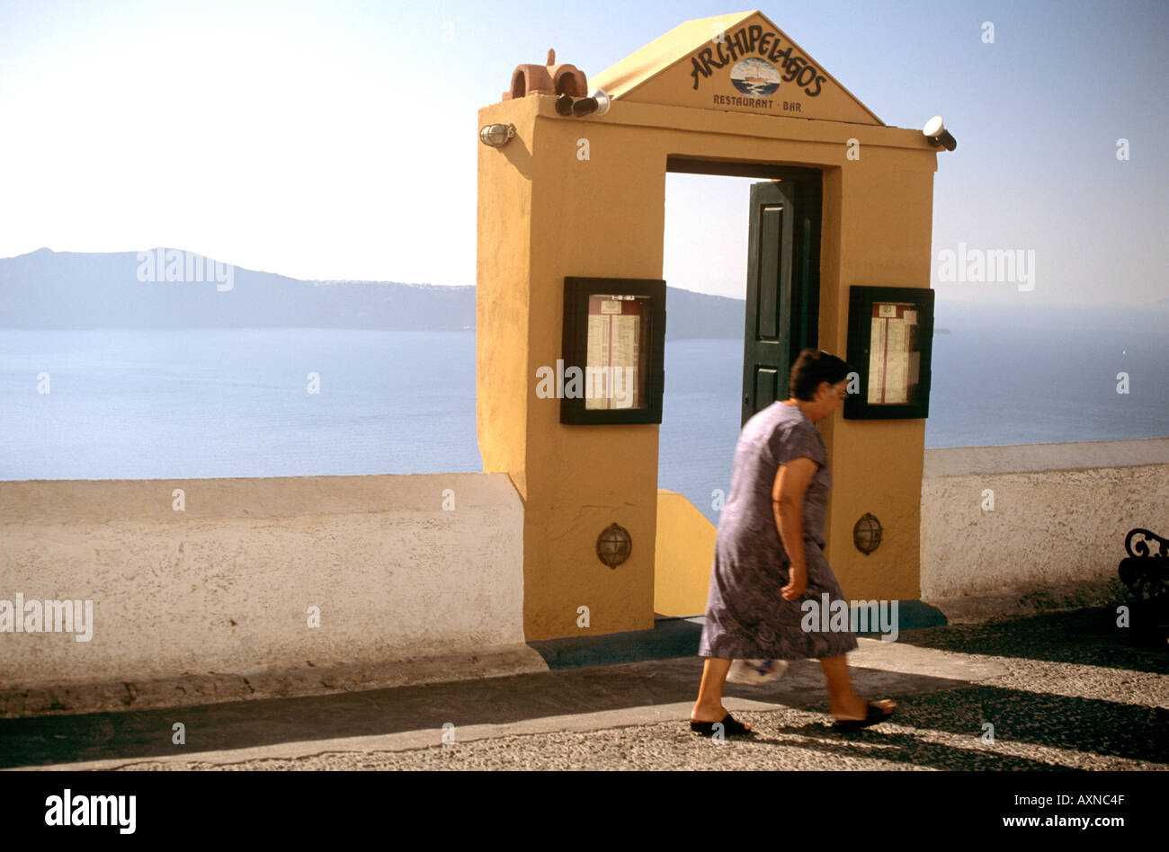 Dame grecque en passant devant l'entrée du restaurant d'archipels Thira Santorini Les Cyclades Grèce Banque D'Images