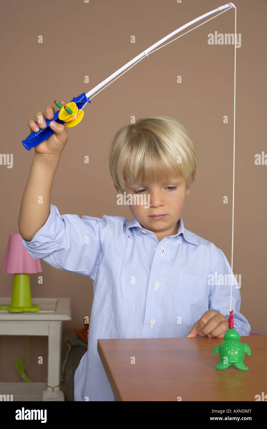 Garçon (4-5 ans) à l'aide d'un jouet canne à pêche Photo Stock - Alamy