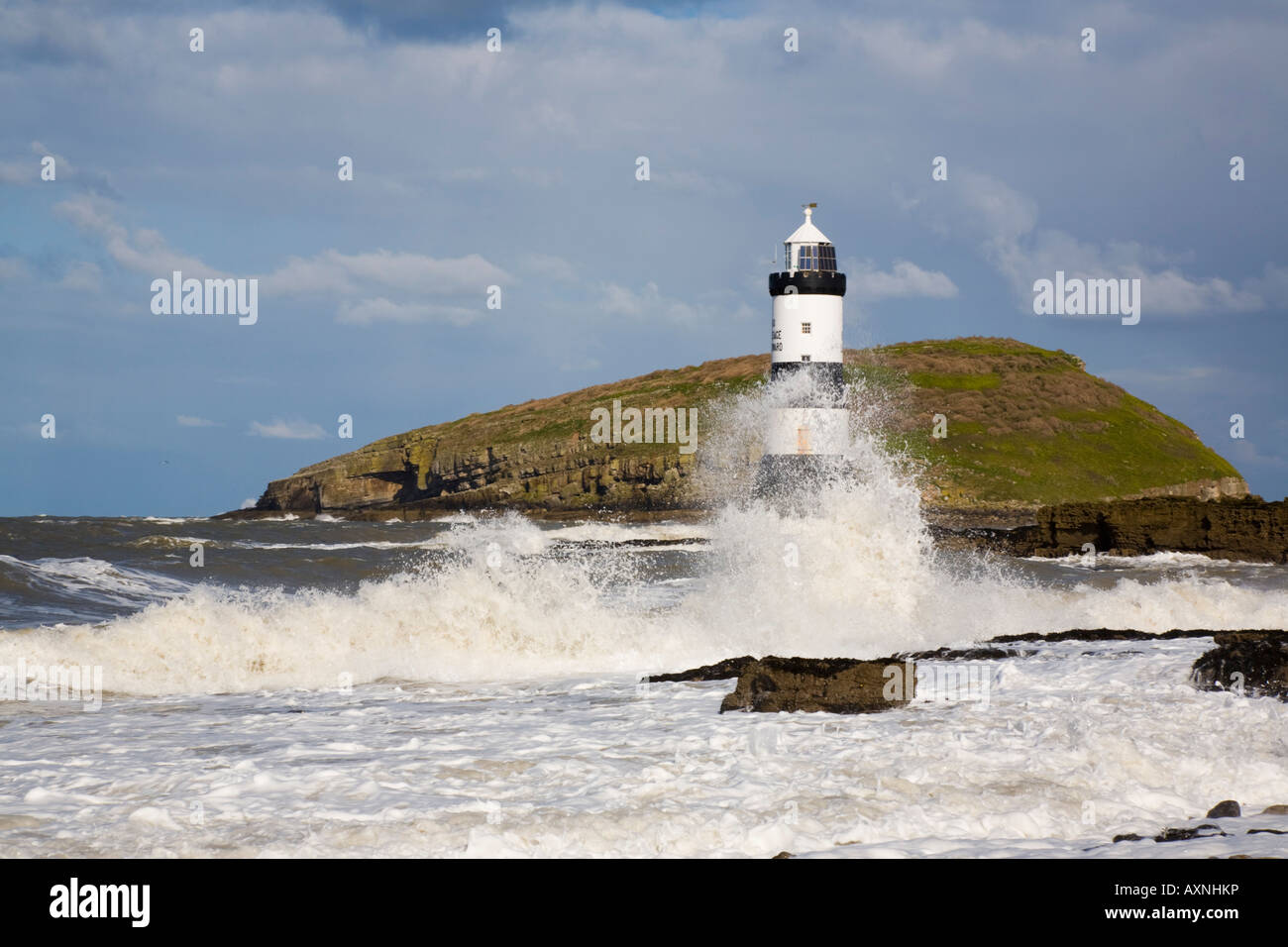 Une mer agitée par les tempêtes de vent Penmon phare et l'île de macareux avec des vagues se brisant sur la côte rocheuse au printemps. Penmon Point Anglesey Pays de Galles UK Banque D'Images