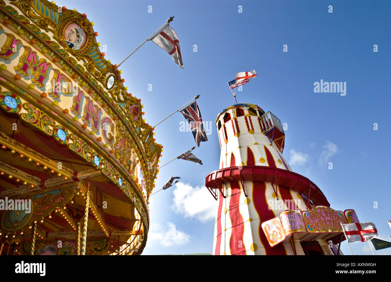 De montagnes russes au parc avec carousel merry-go-round en rayures coloré et l'or avec des drapeaux sous ciel bleu enfant Banque D'Images