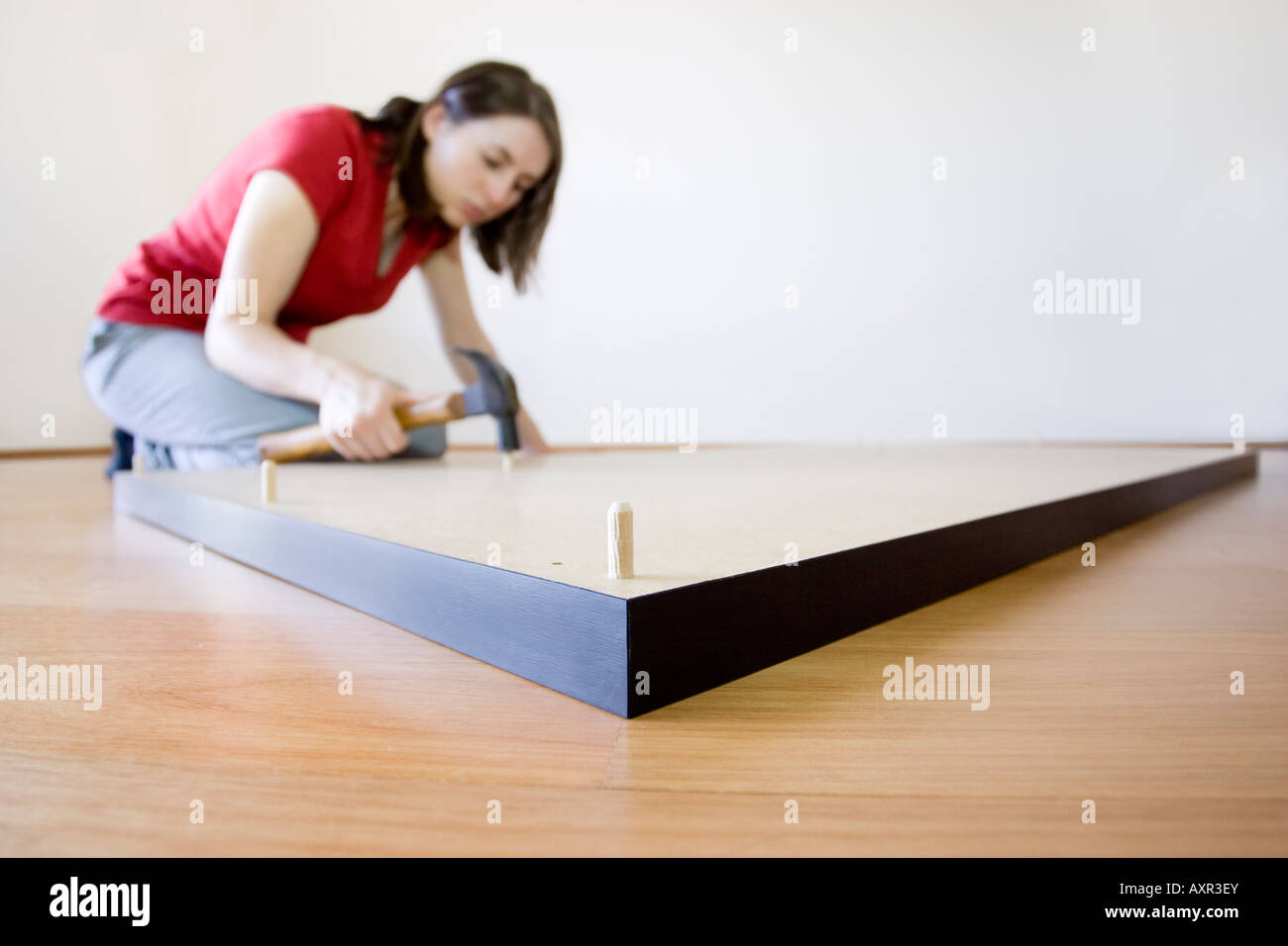 Une jeune femme faisant DIY touchant un goujon sur le dessous d'un flat pack auto-assemblage 24. Banque D'Images