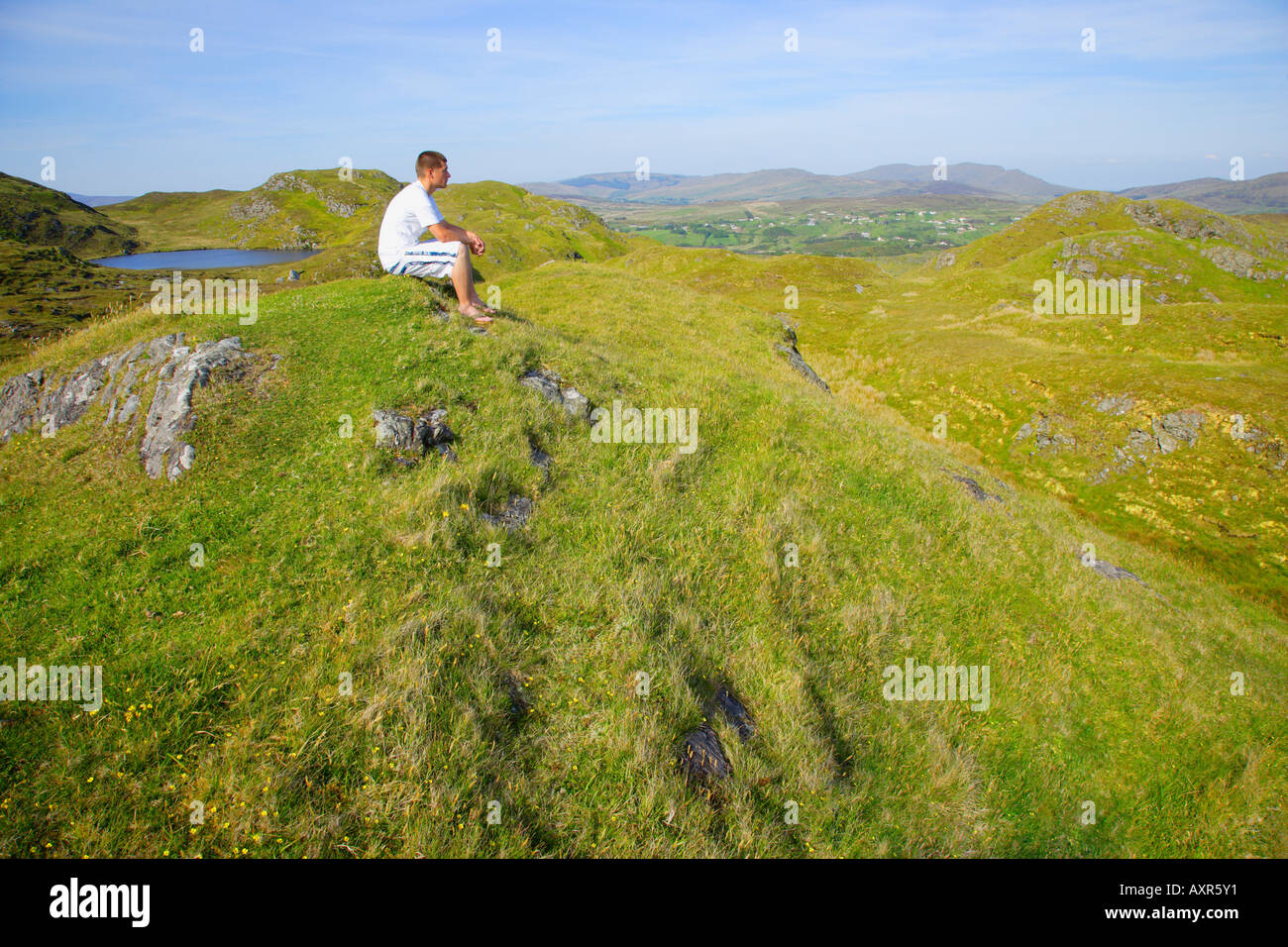 Homme assis au sommet d'une colline Banque D'Images