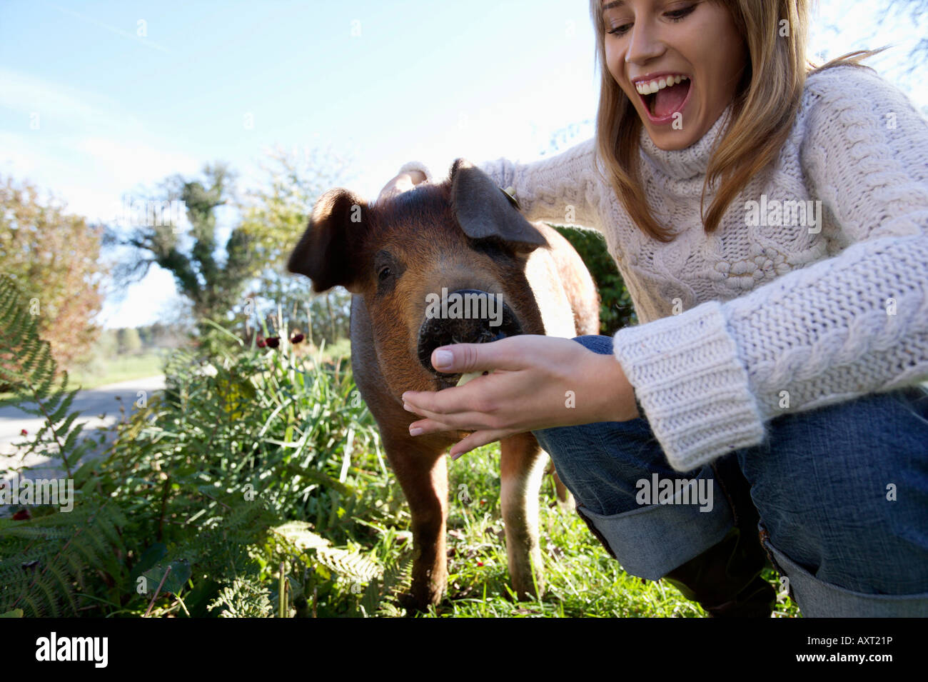 Jeune femme nourrissant un porcelet, close-up Banque D'Images