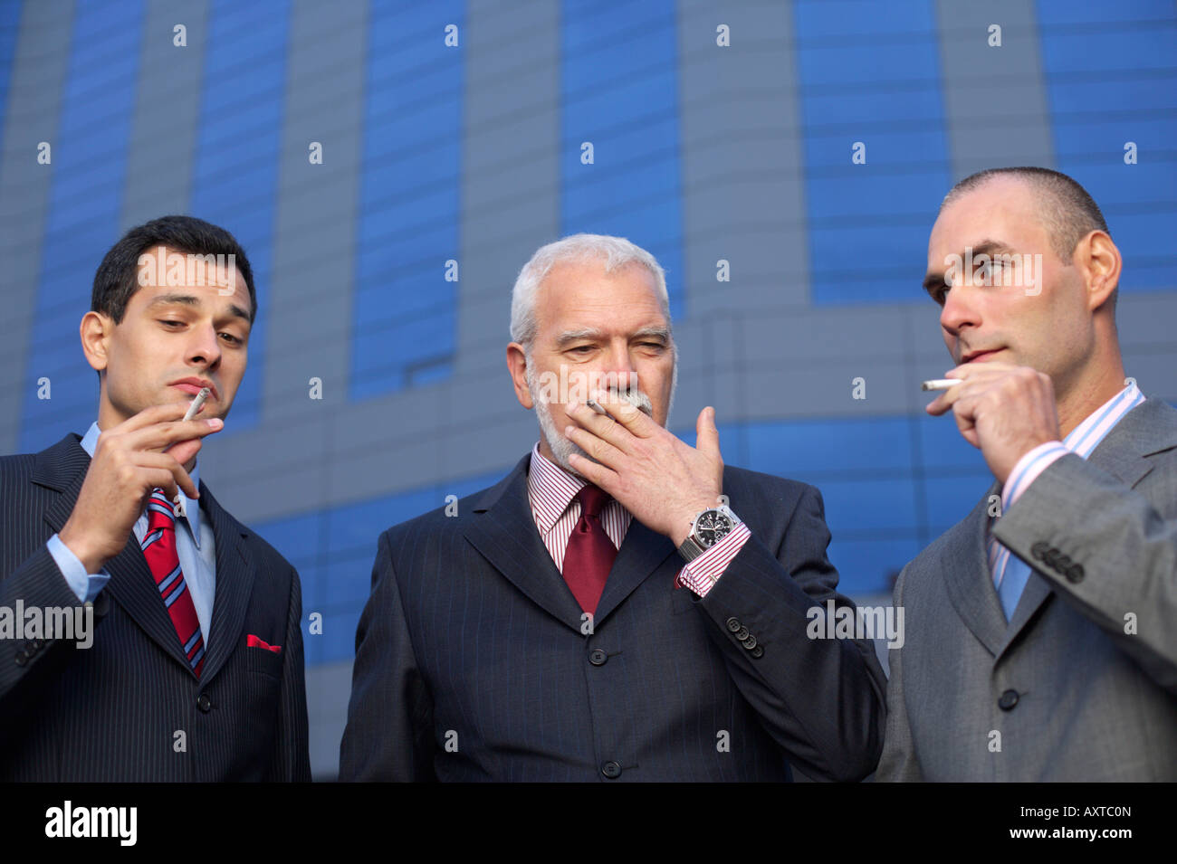 Trois hommes d'fumeurs en face d'un immeuble de bureaux Banque D'Images